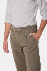 Pantalón de vestir color verde oliva, de corte recto, con bolsillos laterales y traseros. Se ajusta a la cintura con cinturón de cuero marrón.