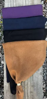 Pañuelo triangular de diseño envolvente, confeccionado en paño de baby alpaca, con forro interior y aro metálico integrado para ajuste frontal.
