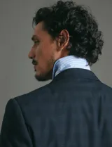 Saco de vestir azul oscuro con textura sutil, corte entallado, cierre frontal de un botón y solapas clásicas.