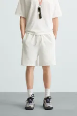 Bermuda de algodón gris con efecto lavado, corte relajado, cintura elástica ajustable con cordón y bolsillos laterales y trasero de vivo.