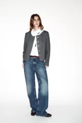 Blazer de corte entallado con cuello redondo, manga larga y hombreras. Presenta cierre frontal con botones dorados y una textura sutil en la tela.