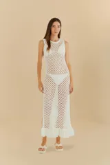 Vestido largo de crochet blanco, sin mangas y con cuello redondo, con un calce al cuerpo y un ruedo con detalle de volado.