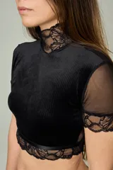 Conjunto de lencería negro compuesto por un top de cuello alto con mangas cortas de microtul y detalles de encaje, y una tanga regulable con aplique de encaje.