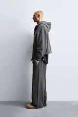 Sudadera con capucha y cierre frontal de cremallera, confeccionada en tejido con efecto lavado. Presenta un corte relajado, bolsillos tipo canguro y parches decorativos en el pecho. Las mangas largas terminan en puños de rib.