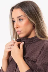 Camisa de broderie color marrón chocolate, con cuello alto, detalles de volados, mangas largas abullonadas y cierre frontal de botones.