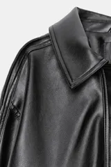 Cazadora de cuero sintético en color negro, con cuello de solapa y aplicación de pelo sintético desmontable. Presenta cierre frontal con cremallera y botones a presión ocultos, bolsillos de plastrón con solapa en el delantero y bajo con elástico.