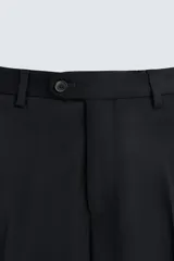 Pantalón de traje regular fit confeccionado en tejido de lana. Presenta bolsillos frontales, bolsillos traseros de vivo con botón y cierre frontal con cremallera y botón.