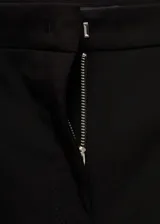 Pantalón negro de corte ajustado y tiro medio, con bolsillos laterales y cierre frontal con cremallera y botón.