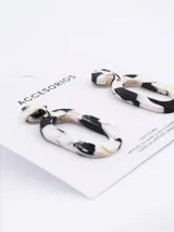 Aros colgantes con forma geométrica irregular, de acrílico con diseño carey en blanco y negro.