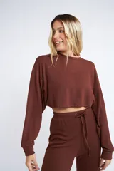 Buzo corto de tejido rib en color verde militar, con mangas largas y cuello redondo. Presenta un diseño holgado y cropped.