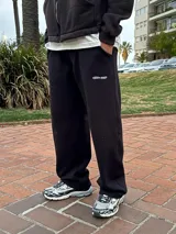 Pantalón de jogging negro de corte holgado, con bolsillos laterales y pequeño logo bordado en la parte superior del muslo.