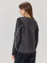 Buzo de lana con escote en V, diseño de rombos y detalles en hilo metalizado. Presenta mangas largas y corte holgado.