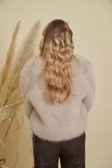 Abrigo corto de piel sintética en tono beige, con cuello redondo y mangas largas. Diseño de corte recto y textura suave.