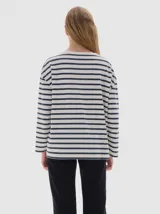 Remera de manga larga con calce holgado, confeccionada en algodón. Presenta un diseño a rayas horizontales en tonos beige y negro, con bordado de letras SP en el pecho y estampa de la marca en la manga.