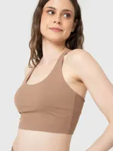 Top deportivo de sujeción media con diseño de espalda cruzada y cuello redondo. Presenta un ajuste al cuerpo y logo pequeño estampado en el pecho.