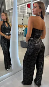 Mono largo negro con estampado sutil, escote halter con cuello alto y abertura en el pecho. Piernas anchas y corte holgado.