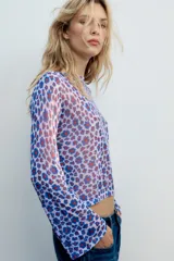 Top de punto fino color lila con estampado de flores abstractas en tonos azules y rojos, con cuello redondo y mangas largas acampanadas.