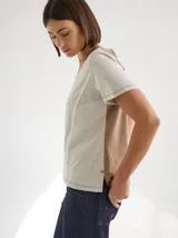 Remera gris de algodón y spandex, de manga corta y cuello redondo. Presenta líneas verticales en blanco y negro. Corte recto.