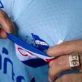 Camiseta de fútbol Umbro del Club Nacional de Football, modelo Away 3. Diseño en color celeste con cuello polo tricolor y detalles en azul, blanco y rojo en las mangas. Incluye logo de Umbro, escudo del club y sponsors estampados en el frente y laterales.