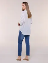 Camisa de calce holgado en género liviano con estampado a rayas verticales, cuello camisero clásico y abotonadura frontal a tono. Presenta mangas largas regulables con presilla y botón para ajustar a tres cuartos, espalda con canesú y suave pliegue central, y ruedo curvo estilo camisero.