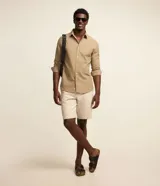 Bermuda masculina slim confeccionada en sarga de algodón con elastano, color beige, de corte ajustado, con bolsillos laterales y traseros con botón.