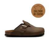Zueco de cuero color marrón, de diseño cerrado tipo mule con una tira ajustable con hebilla metálica en el empeine, suela de corcho y base de goma negra.