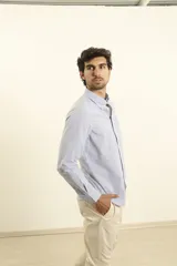 Camisa celeste a rayas verticales, de corte clásico, con cuello button-down y manga larga.
