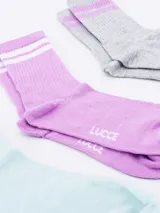 Pack de tres pares de medias de caña corta, con diseño de rayas en la parte superior. Incluye un par celeste con rayas blancas, un par lila con rayas blancas y un par gris con rayas lilas.