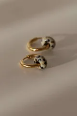 Par de aros tipo argolla dorados de acero quirúrgico, con una piedra natural de color gris translúcido colgando de cada uno.