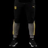 Pantalón de jogging Puma del Club Atlético Peñarol, con diseño colorblock en negro y gris, franjas laterales amarillas, puños elásticos y escudo del club bordado.