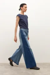 Jean wide leg bicolor en tonos de gris oscuro, con paneles laterales más oscuros y ruedo deshilachado.