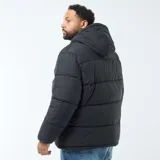Campera acolchada tipo puffer color negro, con capucha fija, cierre frontal completo y bolsillos laterales y en el pecho con cierre.