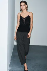 Top de terciopelo negro con escote en pico, tirantes finos ajustables y detalles de encaje a tono en el escote y el bajo.