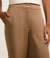 Pantalón wide leg color marrón claro, de tiro alto, con cierre tradicional y doble botón en la cintura.