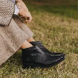 Bota corta de cuero vacuno con acabado metalizado y textura de reptil. Presenta punta fina, cierre lateral interno y taco cuadrado de madera.