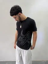Remera de algodón color negro con estampado gráfico abstracto en tono gris en la parte inferior derecha. Presenta cuello redondo reforzado y corte regular.