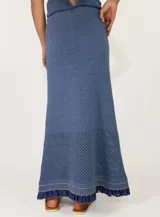 Pollera larga de punto color marrón, con diseño calado en el dobladillo y detalles de volados y costuras en tono rojizo.