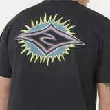 Remera blanca de manga corta y cuello redondo, con un pequeño estampado gráfico en el pecho izquierdo. El diseño es un rombo estilizado con rayos azules y un contorno negro.