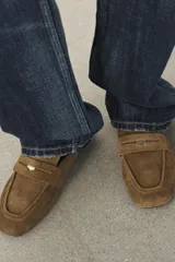 Mocasín destalonado de serraje color marrón, con copete subido, antifaz delantero con detalle metálico y punta cuadrada.