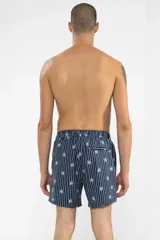 Short de baño azul marino con rayas verticales blancas y estampado de flores azules. Cuenta con cintura elástica con cordón regulable, bolsillos laterales y bolsillo trasero con cierre.