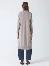 Cárdigan largo de tejido de punto, color beige topo, con mangas largas y botones frontales. Presenta un calce holgado y bolsillos delanteros.