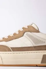 Championes urbanos de diseño moderno, combinando paneles de cuero texturizado en tono tostado y cuero liso en color crema. Presenta una suela de plataforma robusta en tono crema con un detalle en bloque tostado en el talón y un contrafuerte oscuro.
