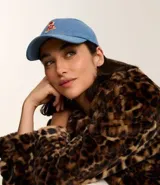 Gorra de jean celeste con visera curva y bordado de un oso en el frente.