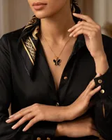 Dije de acero con baño de oro en forma de mariposa con relleno negro.
