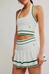 Conjunto deportivo compuesto por un top halter y una pollera pantalón de color blanco con líneas horizontales verdes.