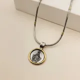 Collar con cadena de eslabones tipo serpiente en plata con detalles en oro, que sostiene un dije circular con la imagen de la Virgen Milagrosa en relieve, enmarcada en un borde de oro.