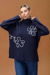 Sweater de punto color azul marino con cuello alto y diseño holgado. Presenta mangas con hombros caídos, terminaciones acanaladas y apliques de líneas orgánicas en relieve de color blanco que forman figuras florales en el frente y las mangas.