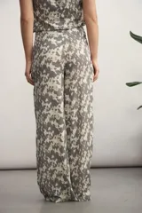 Pantalón de corte recto y tiro alto, confeccionado en tela fluida con estampado abstracto en tonos negro y beige.