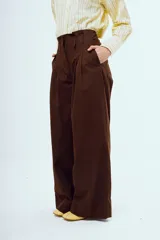 Pantalón marrón de corte ancho y talle alto, con pinzas frontales y bolsillos laterales.