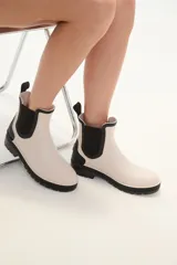 Botas de lluvia bajas color beige con elástico lateral negro y suela de goma negra.